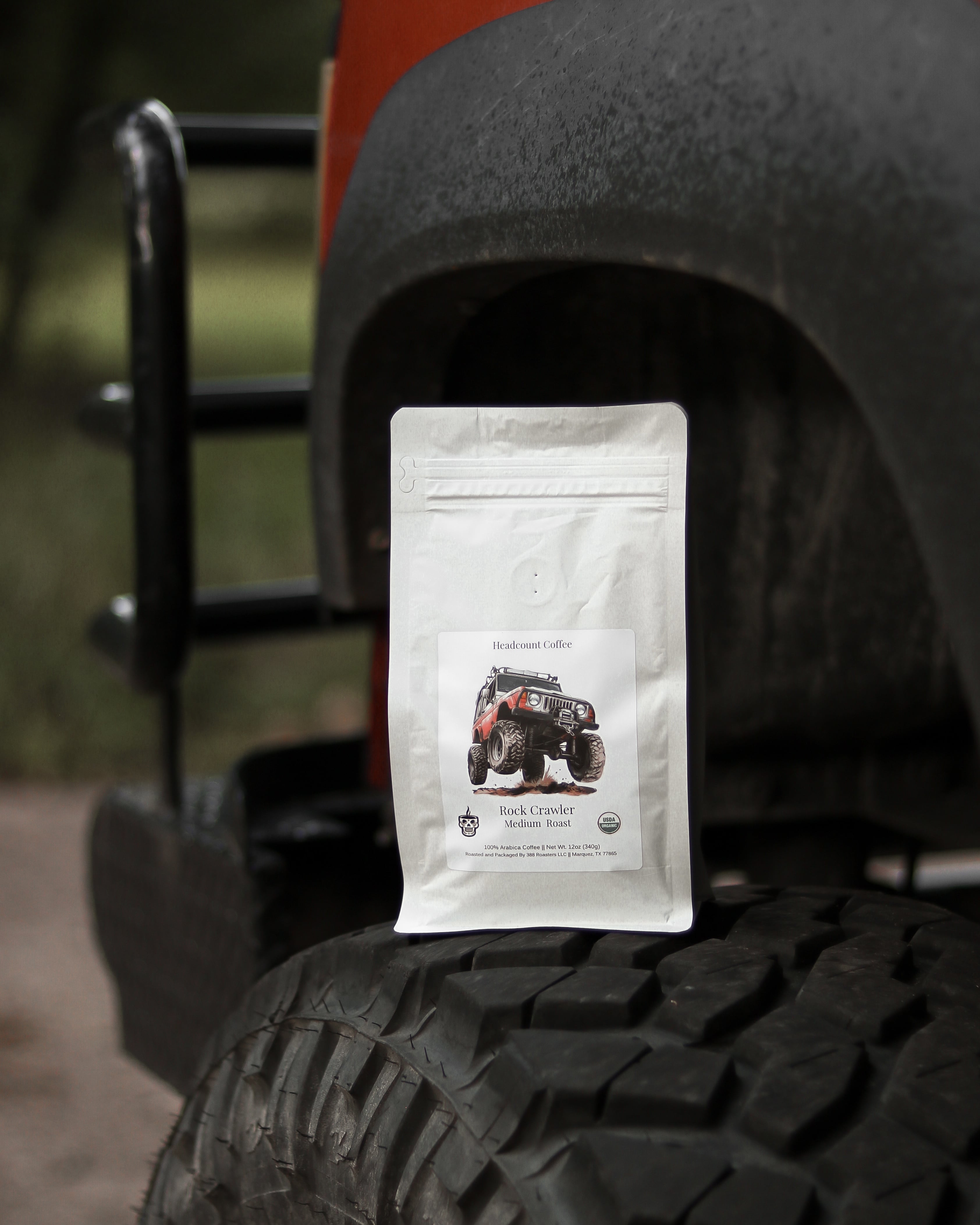 A bag of Headcount Coffee Rock Crawler coffee displayed on the tire of an off-road vehicle.