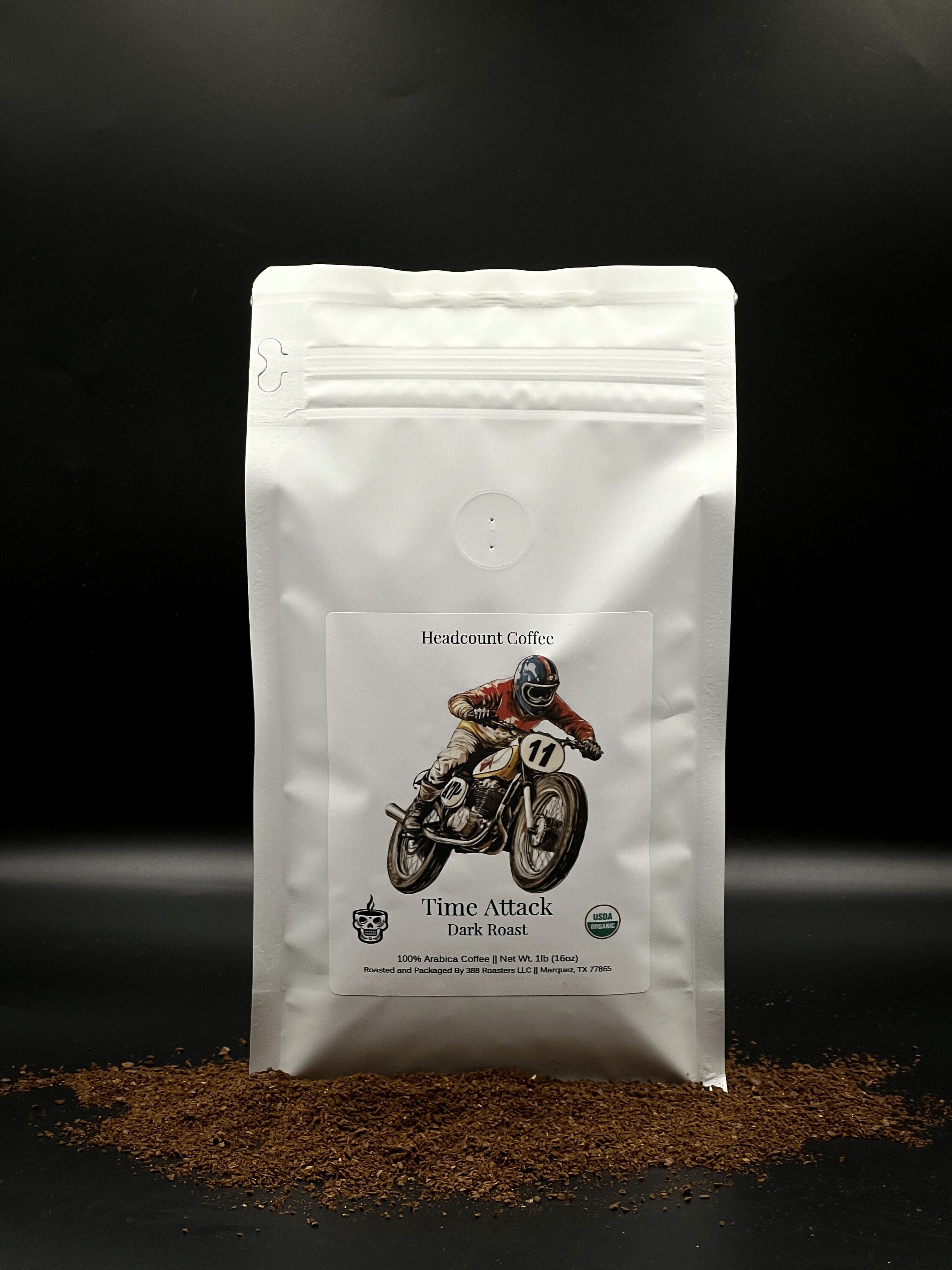 A Headcount Coffee bag of Time Attack coffee with a graphic of a motorcycle on the front, set against a dark background with a scattering of coffee beans in front.