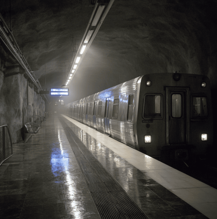 Ghostly silver metro train resembling Sweden’s Silverpilen arriving at an empty station late at night.