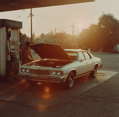 A 1970s American sedan with its hood open for diesel engine repairs, symbolizing the failed U.S. diesel car experiment.