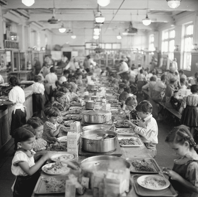 A 1940s school cafeteria scene with children receiving hot lunches from staff, symbolizing the birth of the National School Lunch Program.