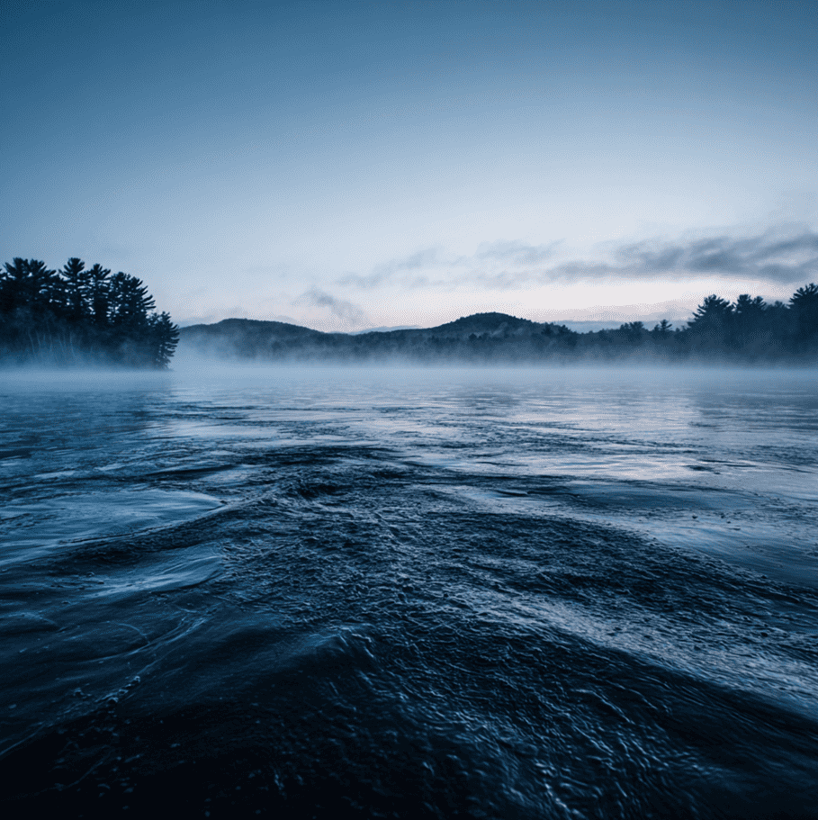 Silhouette of a long, multi-hump creature breaking the surface of Lake Memphremagog, referencing reported monster sightings.