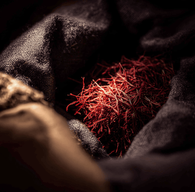 Bundles of deep red saffron threads hidden among trade goods, symbolizing global smuggling and high value spice trafficking.