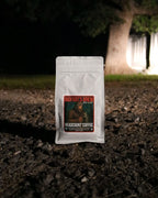Headcount Coffee package labeled 'Bigfoot's Brew' on a dark ground with a blurred natural background