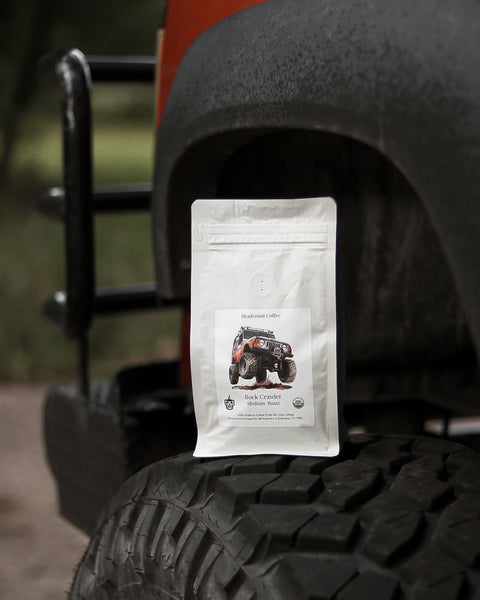 A bag of Headcount Coffee Rock Crawler coffee displayed on the tire of an off-road vehicle.